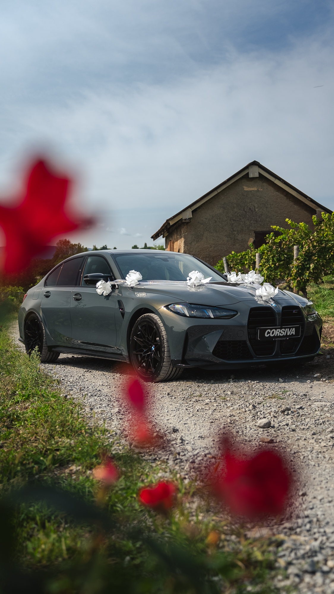 BMW M3 Competition décorée de rubans blancs dans les vignes de Savoie