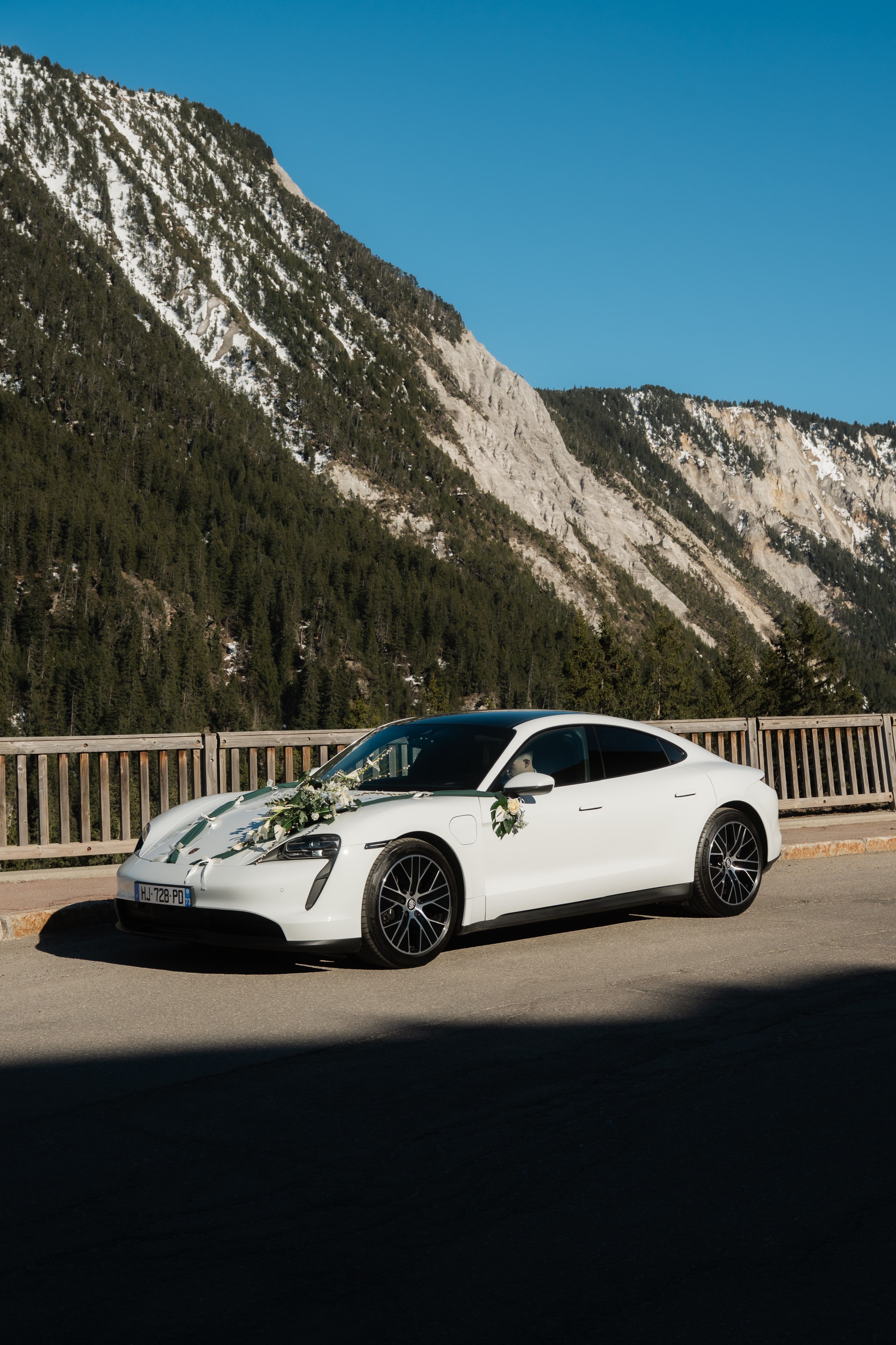Porsche Taycan blanche rubannée sur un pont de montagne à Courchevel
